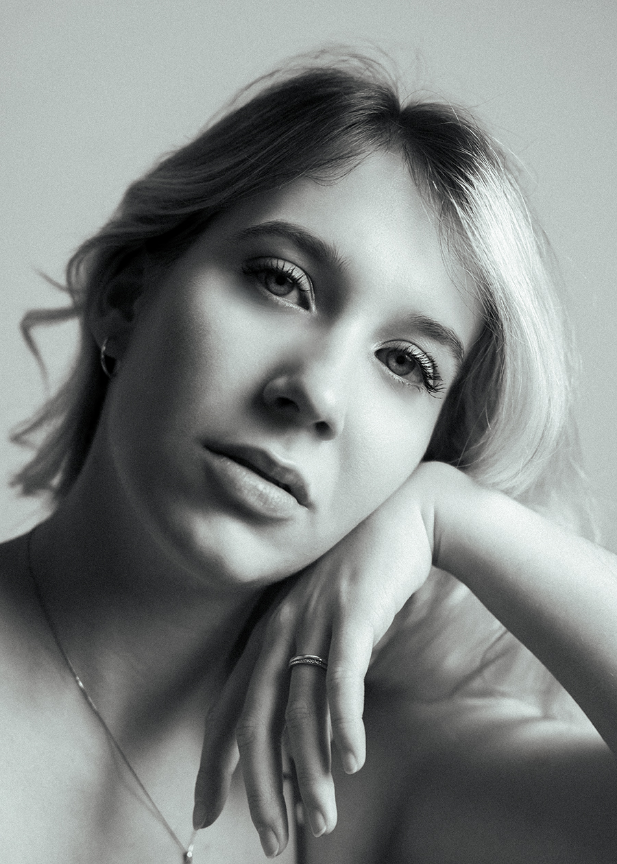 Black and white portrait of woman sitting and leaning on chair